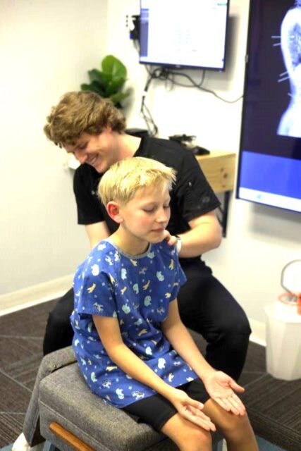 a boy sitting on a chair with a man behind him