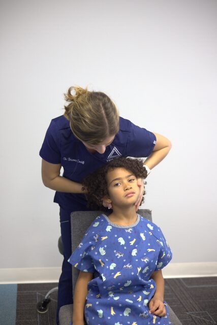 Kid sitting down with a woman behind her